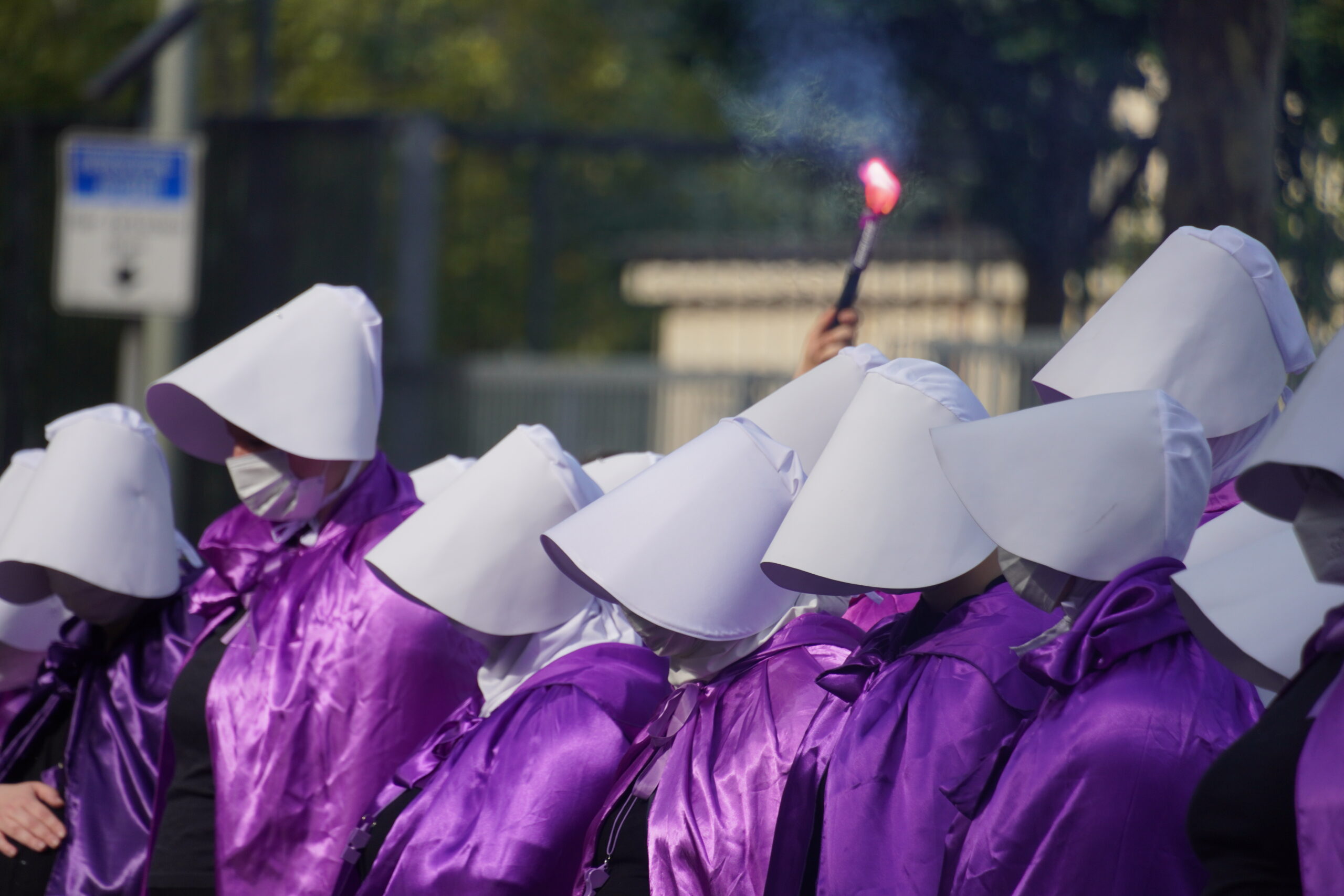 The Handmaids Riots. In lila Gewänder und weiße Schirmkappen gekleidet Frauen.